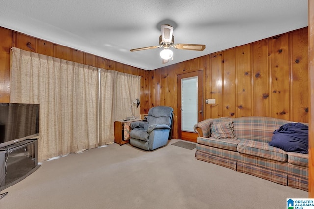 living room with light carpet, wood walls, a textured ceiling, and a ceiling fan