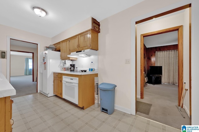 kitchen with light colored carpet, under cabinet range hood, white appliances, light countertops, and brown cabinets