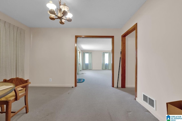 interior space featuring light carpet, baseboards, visible vents, and an inviting chandelier