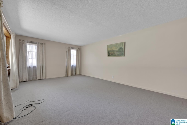 spare room with light carpet, a textured ceiling, and baseboards