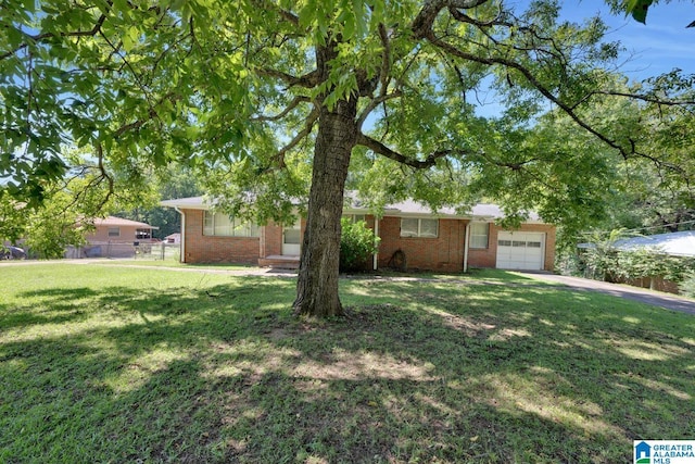 view of front facade with a garage, fence, a front lawn, and brick siding