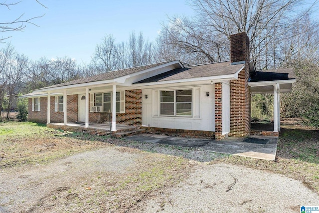 single story home featuring covered porch, a chimney, and brick siding