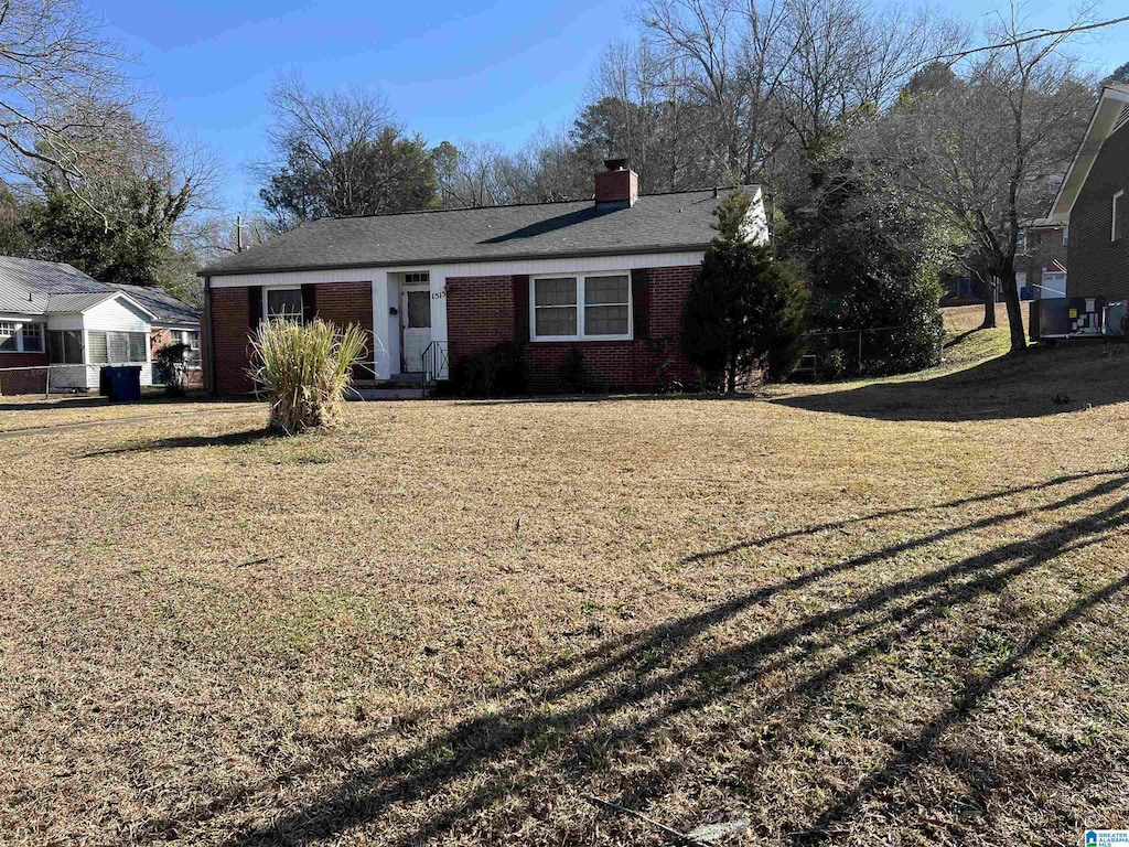 ranch-style home with a chimney, a front lawn, and brick siding