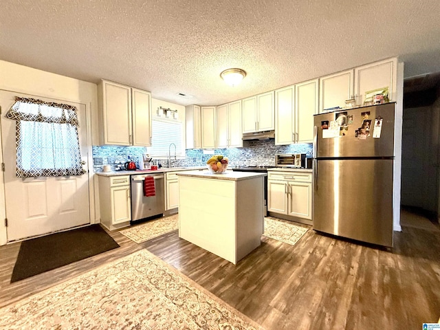 kitchen with tasteful backsplash, dark wood-type flooring, stainless steel appliances, light countertops, and under cabinet range hood