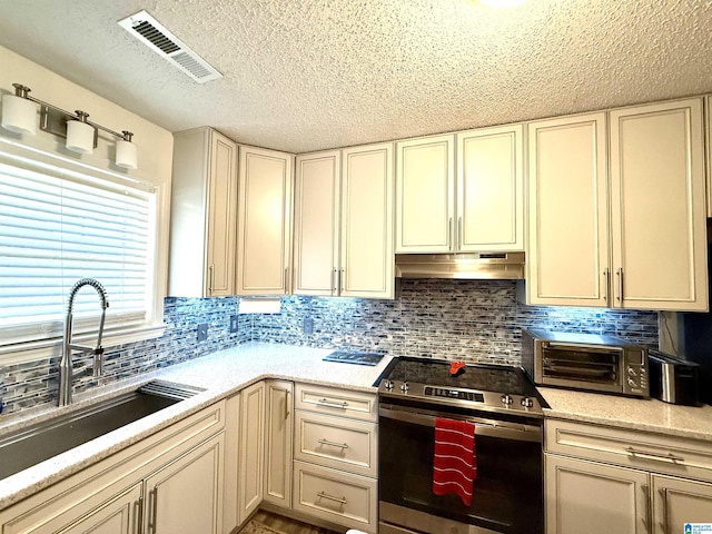 kitchen featuring stainless steel electric range oven, visible vents, light countertops, a sink, and under cabinet range hood