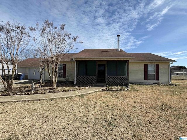 view of front of house with a sunroom, an attached garage, and a front lawn