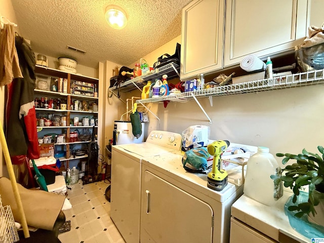 laundry room with washing machine and dryer, visible vents, cabinet space, and a textured ceiling