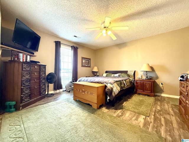 bedroom featuring baseboards, visible vents, ceiling fan, wood finished floors, and a textured ceiling