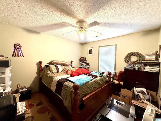 bedroom with a textured ceiling, wood finished floors, visible vents, and a ceiling fan