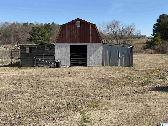 view of barn with a lawn and fence