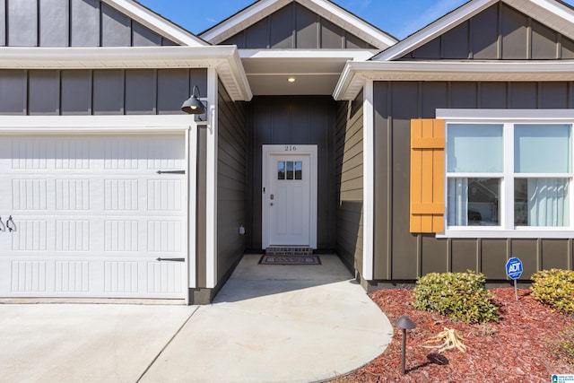 doorway to property with board and batten siding, driveway, and an attached garage