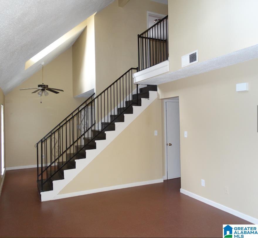 stairs featuring high vaulted ceiling, a skylight, a ceiling fan, and baseboards