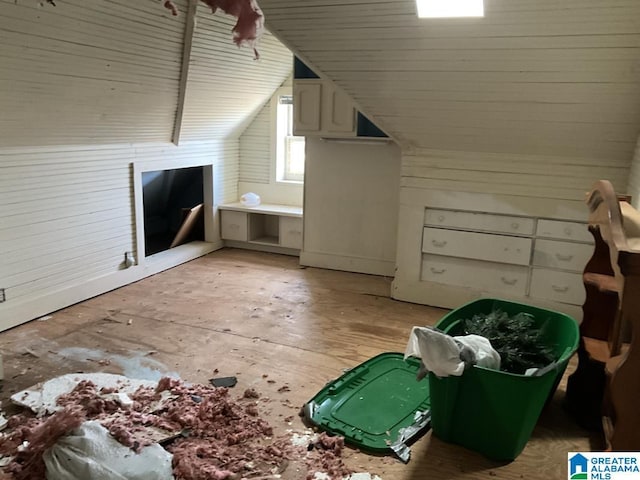 additional living space featuring light wood-type flooring, vaulted ceiling, and wood walls