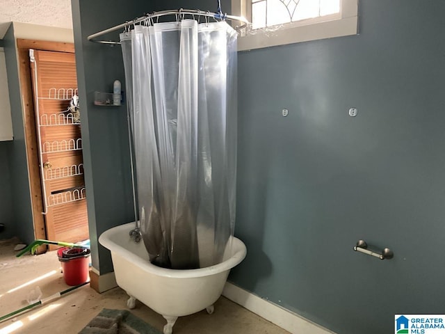 bathroom featuring a textured ceiling, shower / tub combo, and baseboards