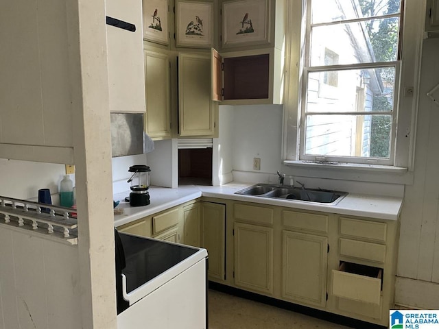 kitchen featuring cream cabinets, light countertops, a sink, and electric stove