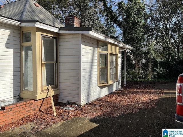 view of side of home featuring a chimney and metal roof