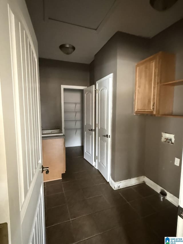 laundry area featuring hookup for a washing machine, dark tile patterned flooring, cabinet space, and baseboards