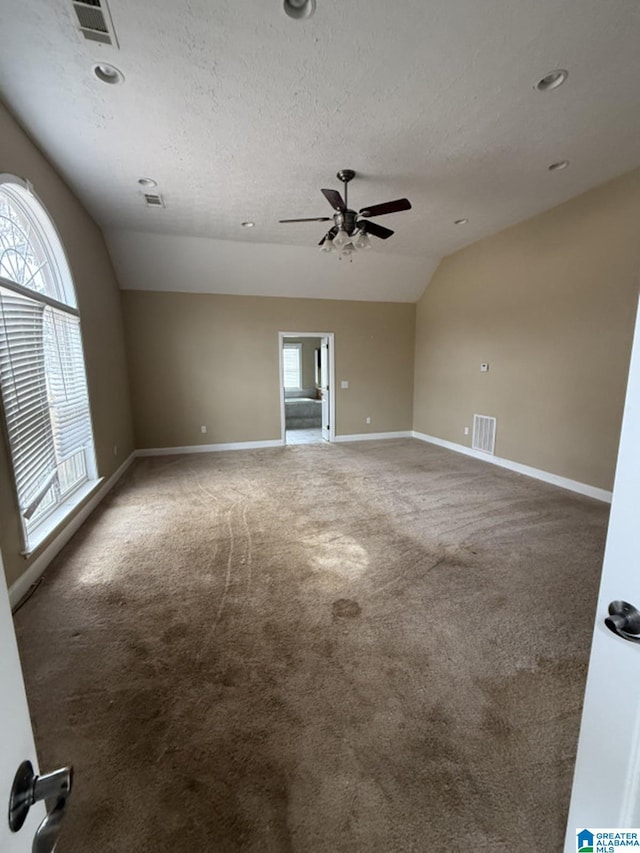 empty room with lofted ceiling, a wealth of natural light, and visible vents