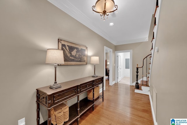 foyer entrance featuring baseboards, stairs, light wood-type flooring, electric panel, and crown molding