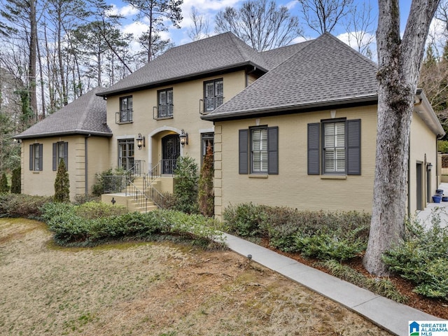 view of front of property featuring a shingled roof and brick siding