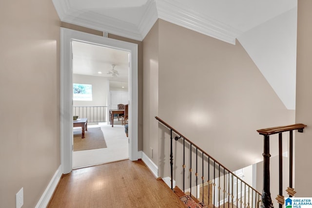 corridor with ornamental molding, wood finished floors, an upstairs landing, and baseboards