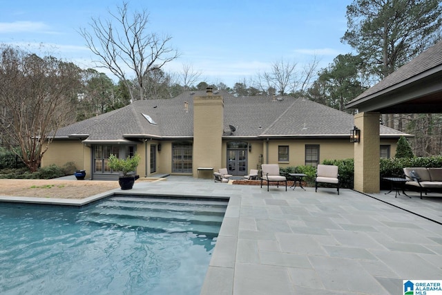 outdoor pool with french doors and a patio