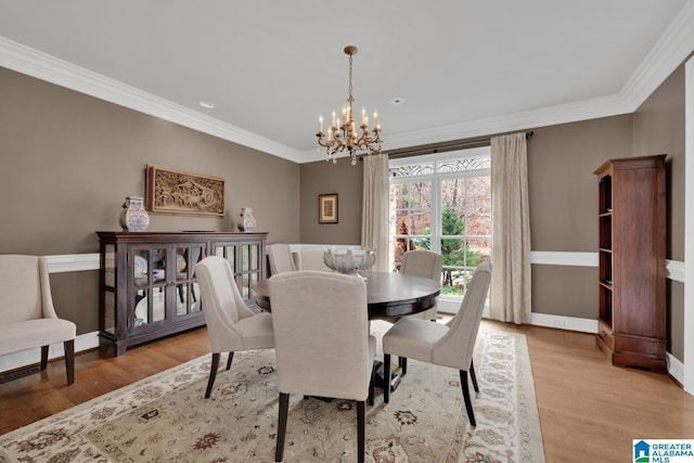 dining space featuring ornamental molding, a chandelier, and wood finished floors