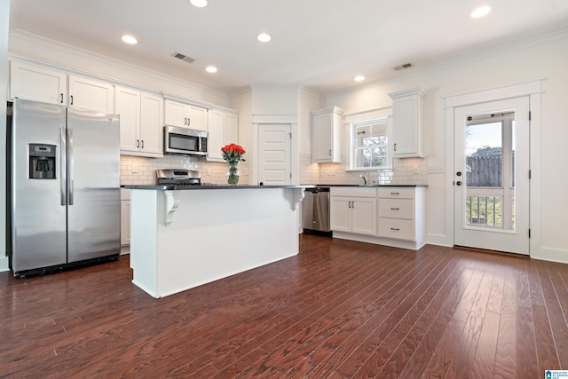 kitchen with stainless steel appliances, dark countertops, visible vents, white cabinets, and a kitchen island