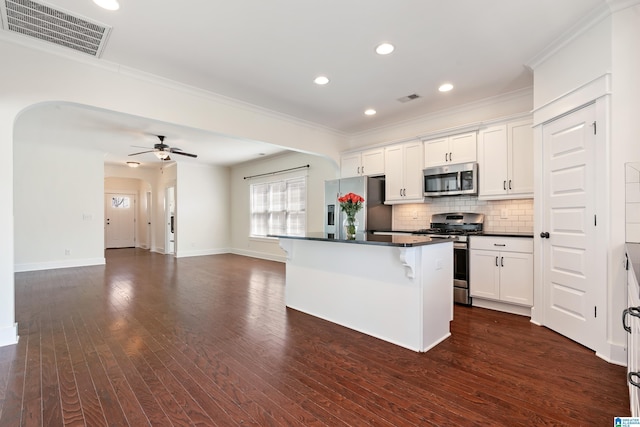 kitchen with a center island, dark countertops, visible vents, appliances with stainless steel finishes, and open floor plan