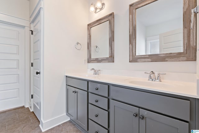 bathroom with double vanity, a sink, and baseboards