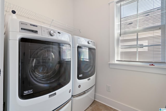 laundry area featuring separate washer and dryer, plenty of natural light, and light tile patterned flooring