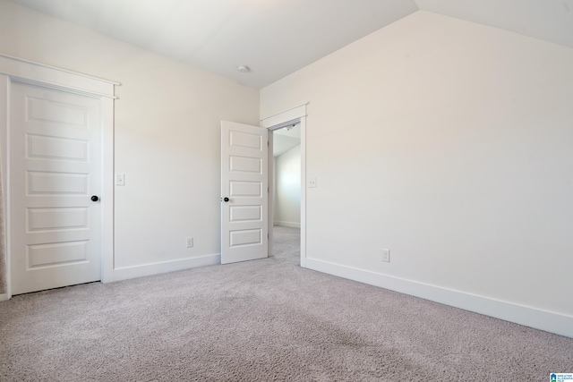 unfurnished bedroom featuring lofted ceiling, baseboards, and carpet flooring