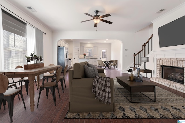 living area with arched walkways, dark wood-style flooring, and crown molding