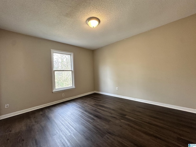 unfurnished room featuring a textured ceiling, dark wood-type flooring, and baseboards