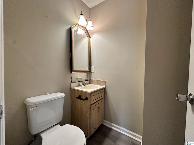 half bath featuring toilet, baseboards, wood finished floors, and vanity