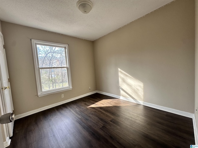 empty room with baseboards, dark wood finished floors, and a textured ceiling