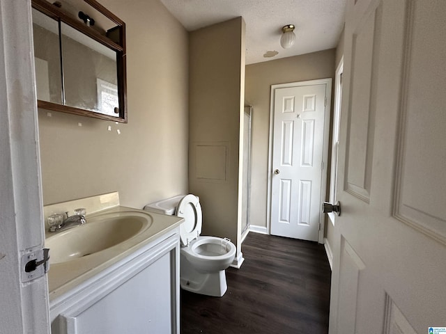 full bathroom with toilet, a textured ceiling, wood finished floors, and vanity