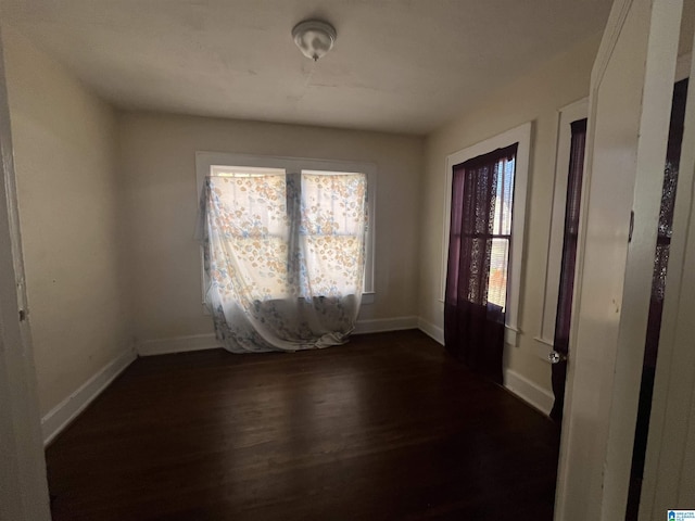 empty room featuring dark wood-style floors and baseboards