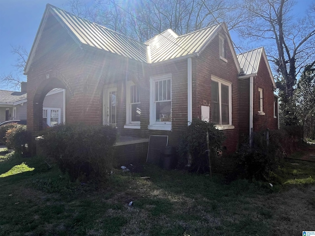 view of front facade featuring a standing seam roof, metal roof, and brick siding