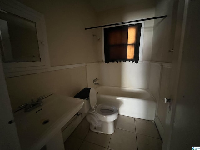 bathroom with bathing tub / shower combination, toilet, a wainscoted wall, tile patterned flooring, and a sink