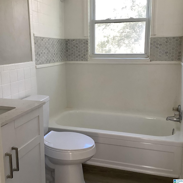 bathroom featuring toilet, a bath, vanity, and tile walls