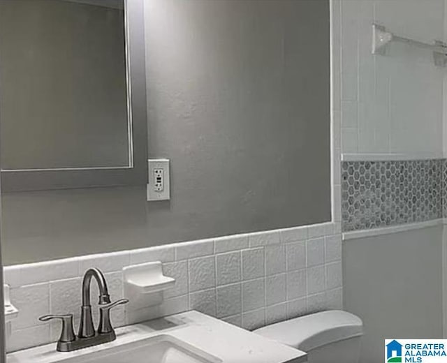 bathroom with toilet, tile walls, and vanity