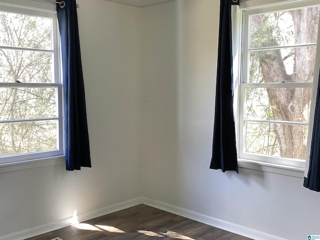 unfurnished room with dark wood-style flooring and baseboards