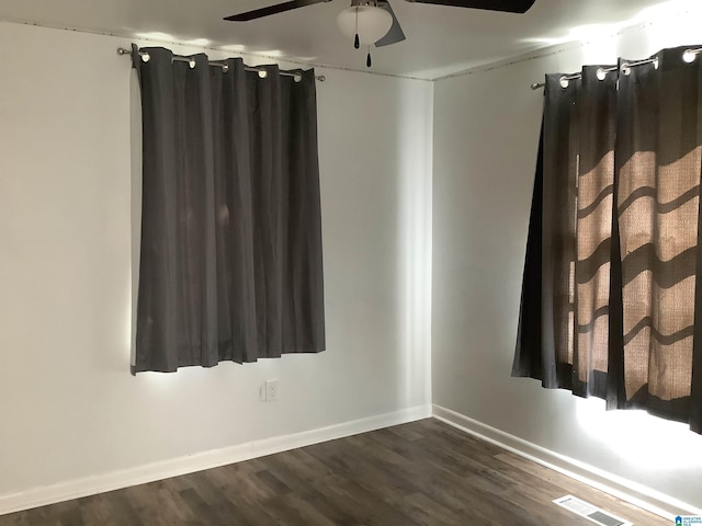 unfurnished room featuring a ceiling fan, dark wood-style flooring, visible vents, and baseboards