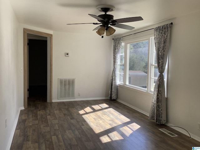 empty room featuring ceiling fan, dark wood-type flooring, visible vents, and baseboards