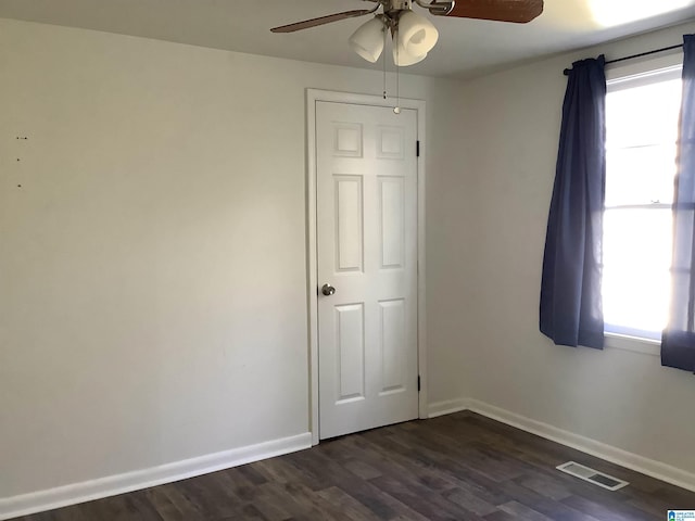 unfurnished bedroom with dark wood-style flooring, multiple windows, visible vents, and baseboards