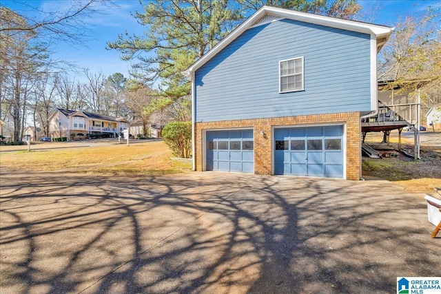 view of side of home featuring driveway, a garage, and brick siding