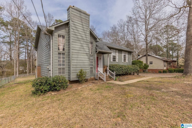 view of front of property featuring a front yard, roof with shingles, fence, and a chimney