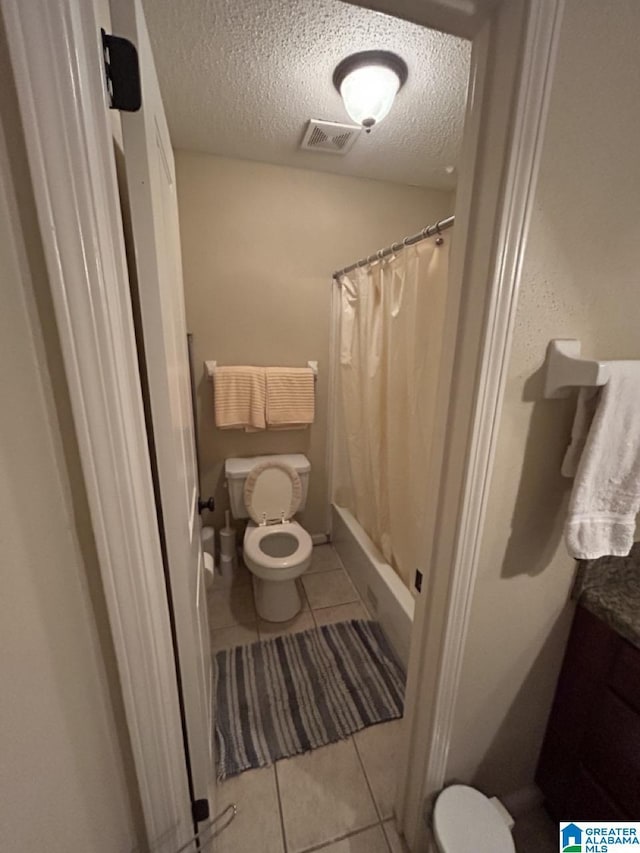 bathroom with a textured ceiling, curtained shower, toilet, visible vents, and tile patterned floors