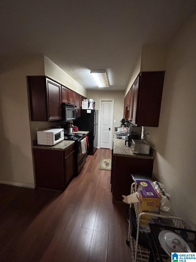 kitchen with light stone countertops, black appliances, baseboards, and wood finished floors